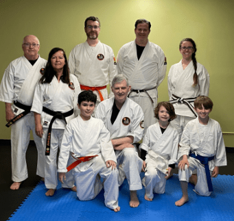 Image of a group of men, women, and children wearing karate clothes and posing for a picture