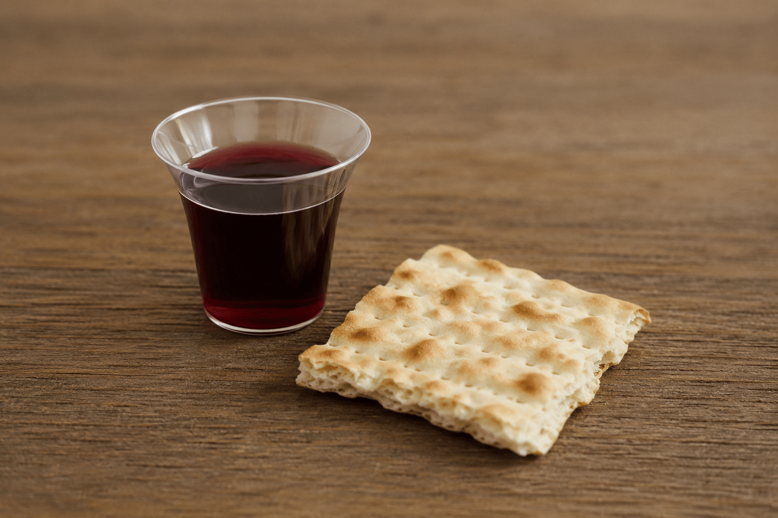 Communion – juice and wafer A wafter and small cup of juice sit on a brown table
